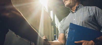 Man in hardhat and clipboard shaking hands