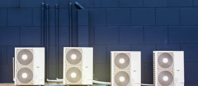 Four white computer speakers on a table