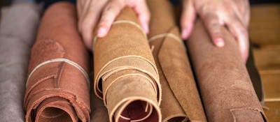 A pair of hands holds rolled leather sheets