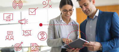 Two employees reviewing data on a tablet with icons around them