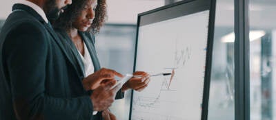 Shot of a young businessman and businesswoman using an interactive whiteboard to analyse data in a modern office