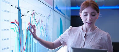 woman pointing to a chart on a whiteboard and using an ipad