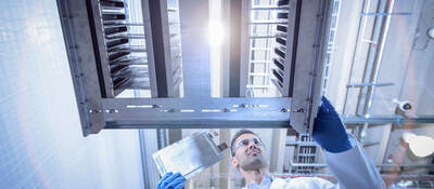 Scientist with lithium ion pouch cell manufacture machine in battery research facility