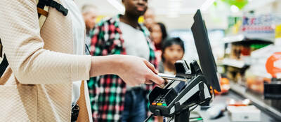 woman using a mobile phone to pay for groceries