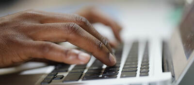 man typing on laptop keyboard