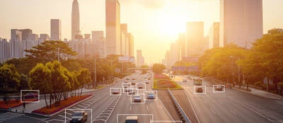 Cars highlighted by artificial intelligence driving down highway with high-rise buildings in the distance