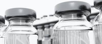 Low-angle photograph of vaccine vial in a freezer, surrounded by freezing fog