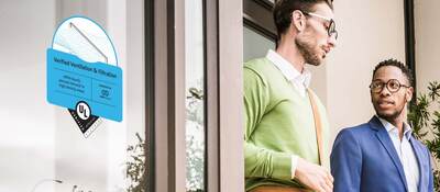 People talking outside of a building that has the Verified Ventilation and Filtration Mark