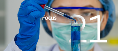 asian scientist putting drops of blue liquid into glass tube