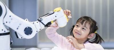 A young girl looking at a robotic arm.