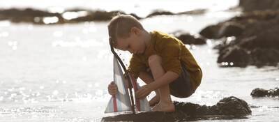 Young boy playing with a toy sailboat