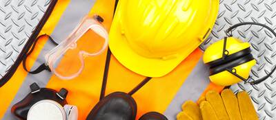 Industrial protective workwear shot from above on diamond-plate background. Includes hard hat, safety glasses, earmuff, gloves, respiratory mask, steel toe shoes and safety vest.