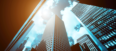 looking up through modern office buildings seeing sun streaming in