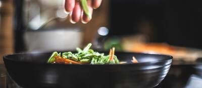 Sprinkling shredded vegetables in a pan for Korean pancakes.