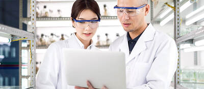 Two laboratory workers looking at a laptop