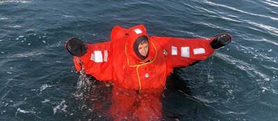 A person wearing an immersion suit and floating in water