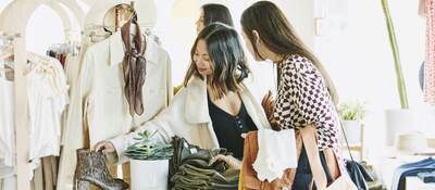 Friends admiring boots while shopping in clothing boutique