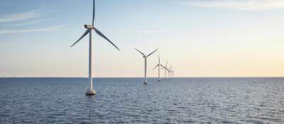 A row of wind turbines stretching across a body of water