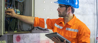 An electrician working at a circuit electrical panel.