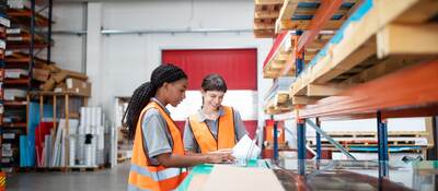 multi ethnic women workers working in a warehouse with a laptop.