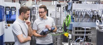 Two men with a control system on factory shop floor.