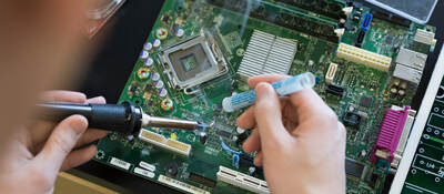 A person using a screwdriver and working on a computer board