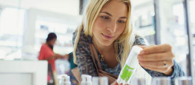 Customer examining skincare product in drugstore