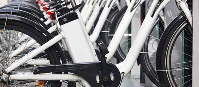 Row of white electric bikes lined up on a bike rack