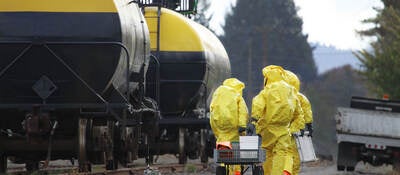 HAZMAT team members investigate chemical disaster near railroad tracks