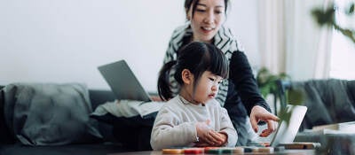 Mother with laptop and child looking at a personal device