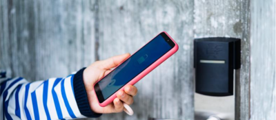 Woman in blue striped shirt holding a smart phone next to a digital lock
