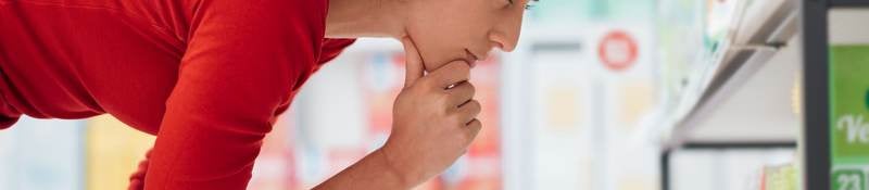 Brown-haired woman looks carefully at a shelf filled over-the-counter medications.