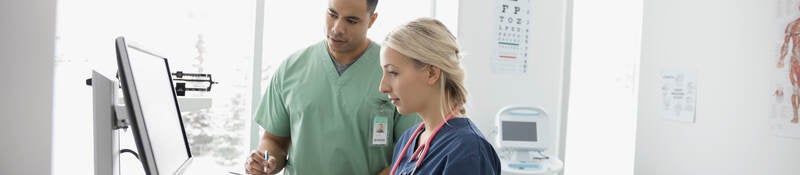 Nurses using computer in clinic examination room