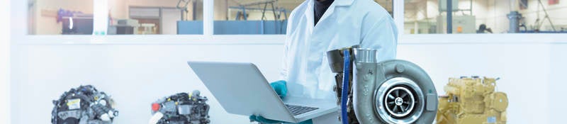 Scientist using laptop in turbo charger automotive research laboratory