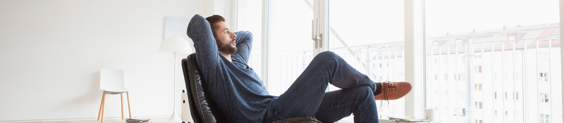 Man relaxing in an armchair conveying a sense of peace of mind, comfort and wellness.