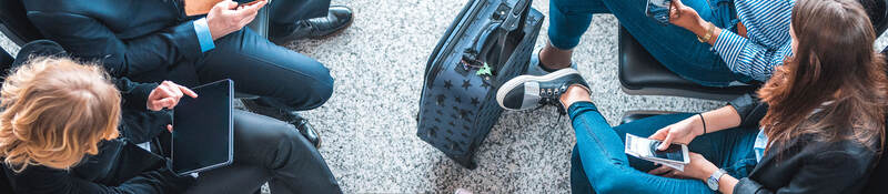 Passengers using mobile devices while waiting at an airport