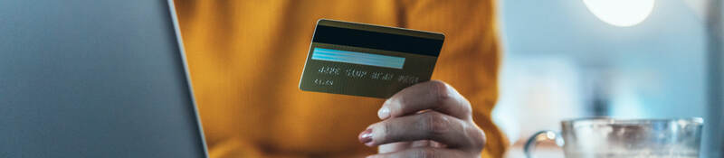 woman holding a credit card and sitting in front of a laptop computer