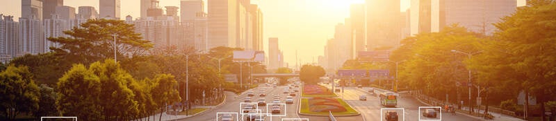 Cars highlighted by artificial intelligence driving down highway with high-rise buildings in the distance