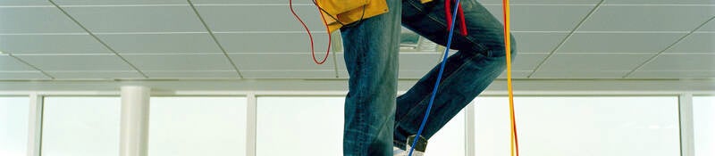 Man on step ladder, working through gap in ceiling, low section