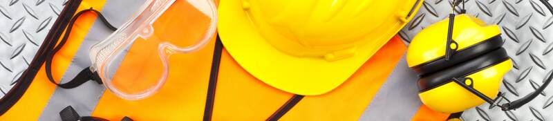 Industrial protective workwear shot from above on diamond-plate background. Includes hard hat, safety glasses, earmuff, gloves, respiratory mask, steel toe shoes and safety vest.