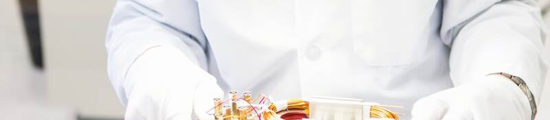 A laboratory worker holding an electrical insulation system with gloved hands