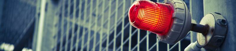 A red emergency light over a commercial building door.