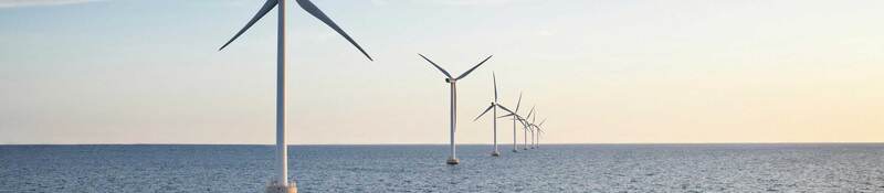 A row of wind turbines stretching across a body of water
