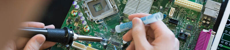 A person using a screwdriver and working on a computer board