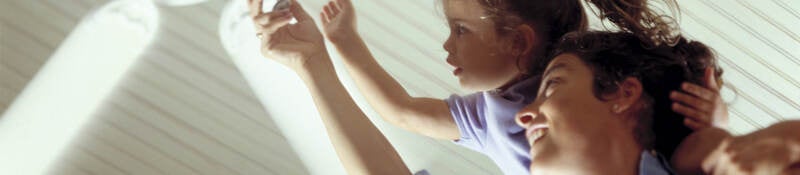 Mother and daughter turning on a ceiling fan.