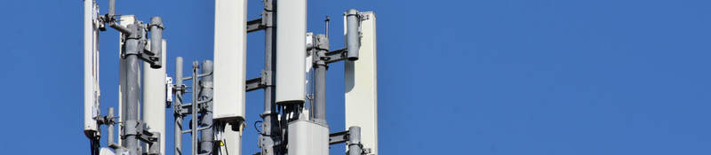 Antennas on a roof with blue sky behind it. 