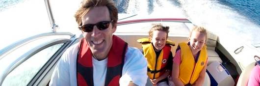 Family of three smiling, boating and wearing life jackets.