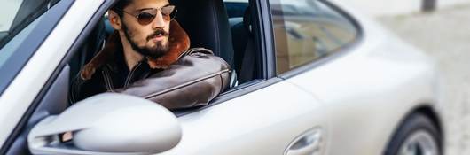 Handsome man sitting in a silver Porche