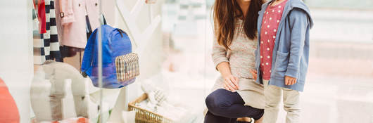 A mother and her daughter look at a clothing store window display in China.