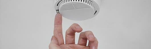 A person pressing a button on a fire alarm. 